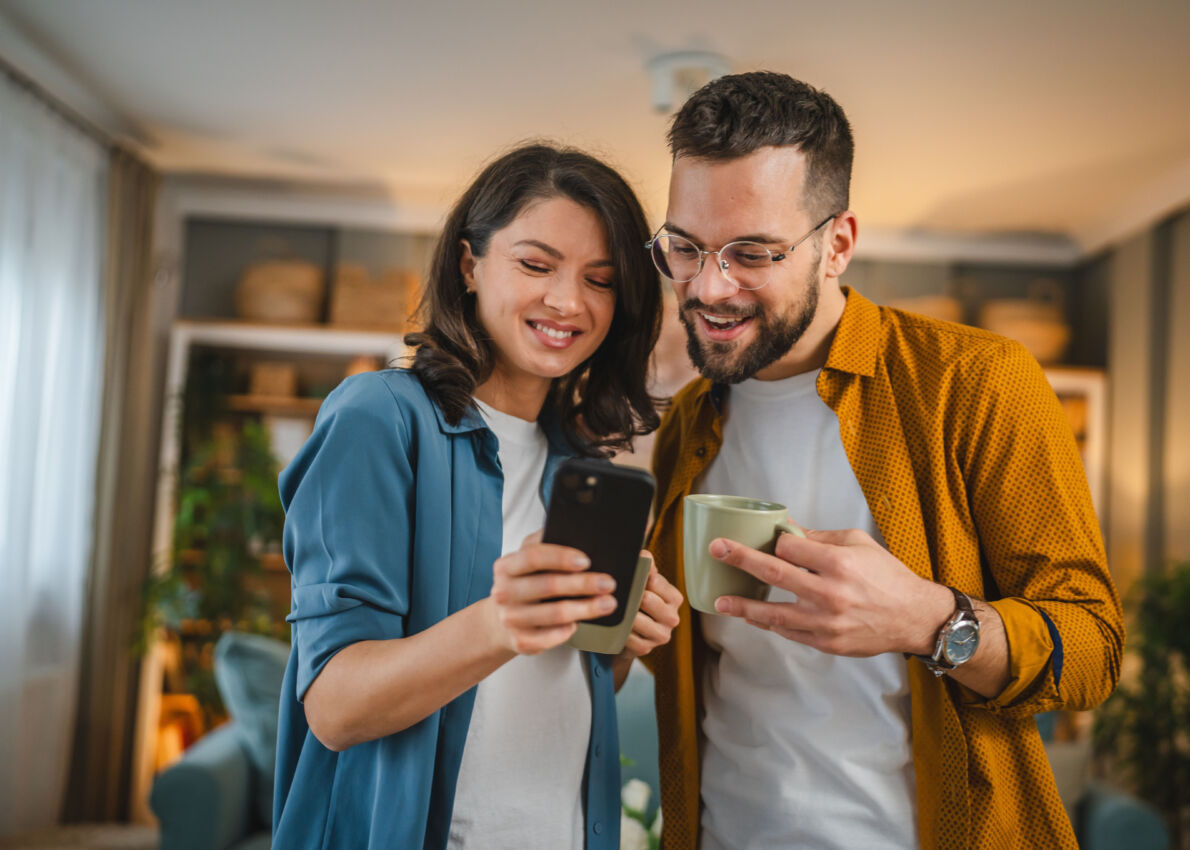 Couple concentré recherchant des conseils pour leur futur projet de logement sur leur smartphone SWCS